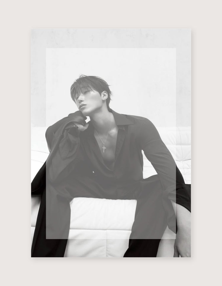 A black and white art print featuring a man in a dark open shirt sitting on a white cushion, displayed against a light beige background.