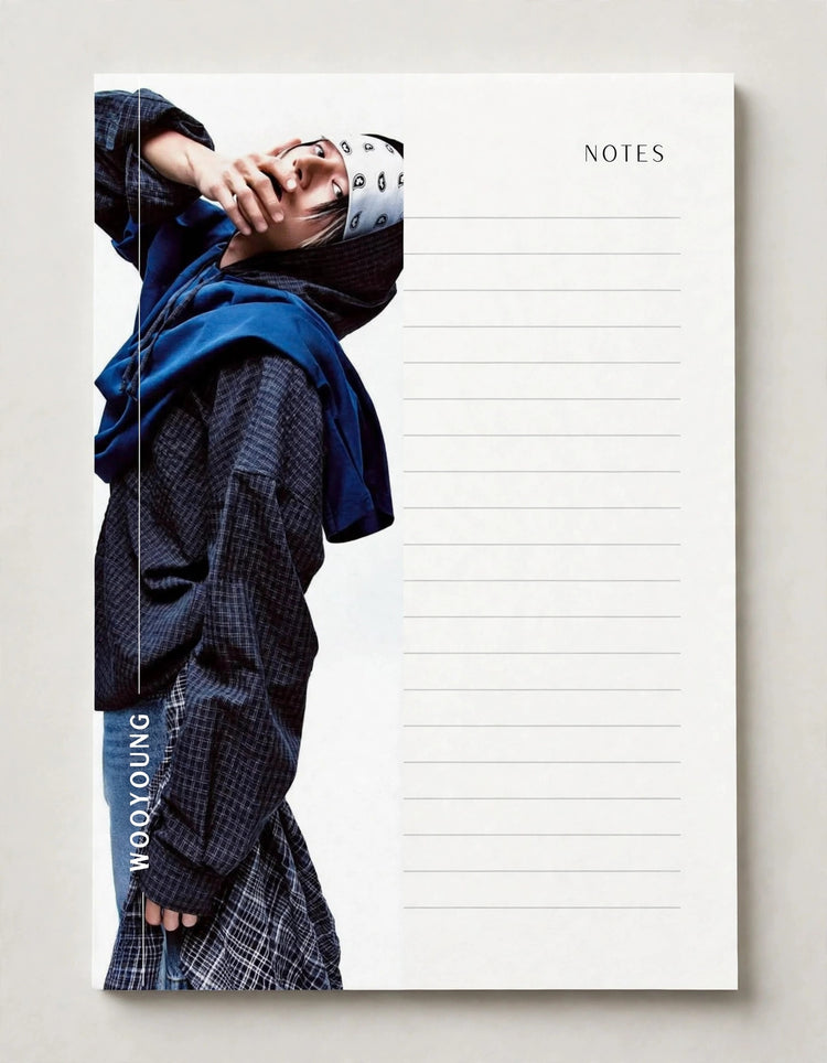 A white lined notepad with the word NOTES printed at the top right, featuring a fashion photo of a person in a dark patterned jacket and blue scarf on the left side, photographed against a light neutral background.