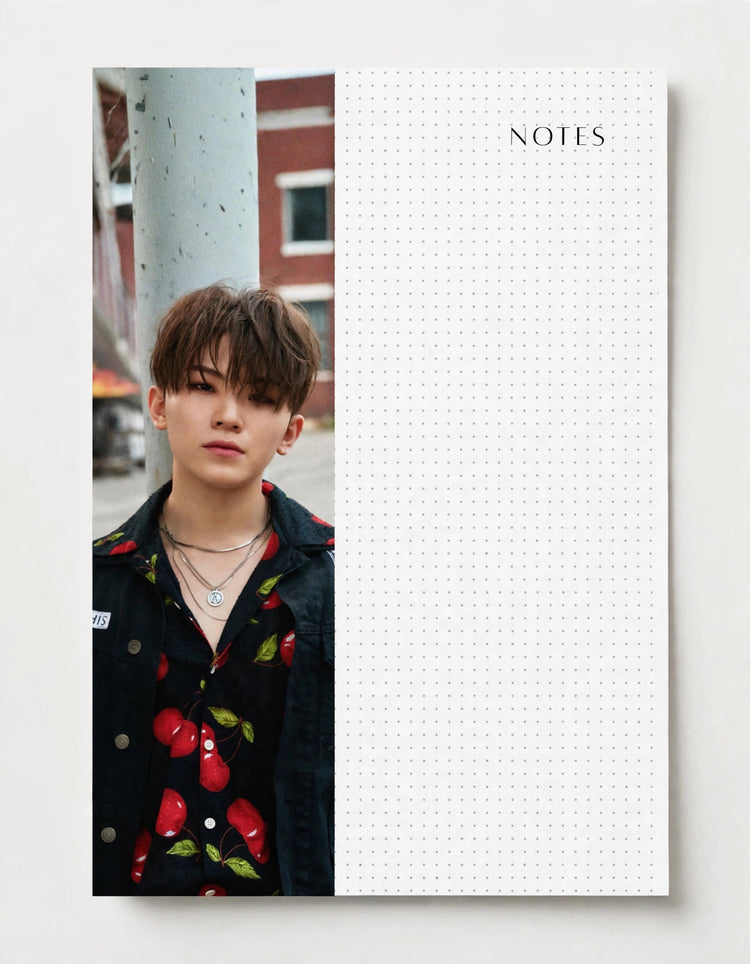 A split-design notebook or planner page shown flat against a light neutral background. The left half contains a vertical portrait photo of a young man wearing a black shirt with red and green cherry print, standing beside a gray pole.